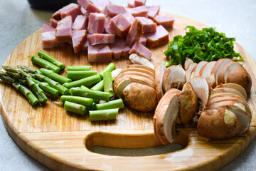 Mushrooms, asparagus and bacon cut on a wooden board.