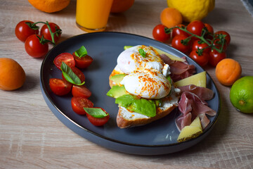 Poached Benedict Egg on a slice of baguette with avocado and cherry tomatoes.