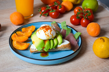 Poached Benedict Egg on a slice of baguette with avocado and cherry tomatoes.