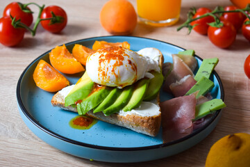 Poached Benedict Egg on a slice of baguette with avocado and cherry tomatoes.