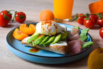 Poached Benedict Egg on a slice of baguette with avocado and cherry tomatoes.