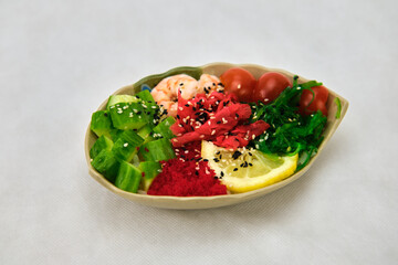 Plate with poke of shrimp, tomato and quinoa on gray background