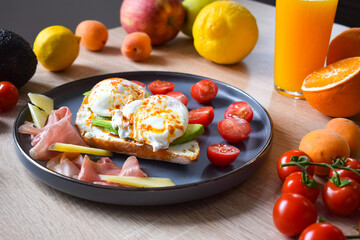Poached Benedict Egg on a slice of baguette with avocado and cherry tomatoes.