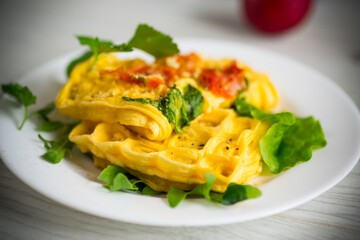 Egg omelet stuffed with tomato and greens fried in the form of waffles