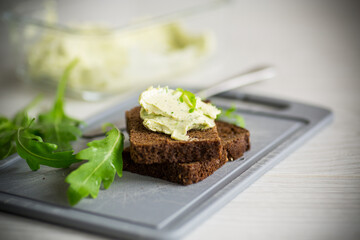 bread cheese spread with garlic and arugula on dark bread
