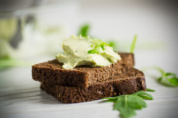 bread cheese spread with garlic and arugula on dark bread