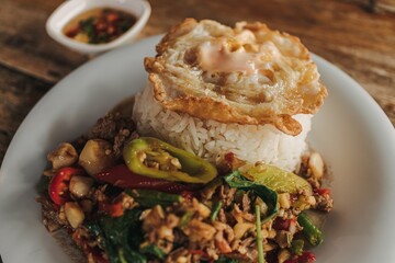 Thai Rice topped with stir-fried minced beef basil and fried egg on white dish.