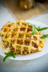 fried potato waffles with cheese in a plate on wooden table.