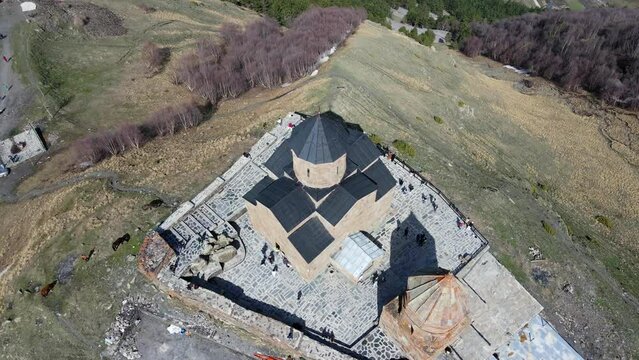 Camera drone ascends above Holy Trinity Church (Gergeti Trinity Church) near the village of Stepantsminda in Georgia