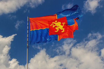 Flag of Krasnoyarsk waving in the wind against the background of a bright blue sky. Blurred motion