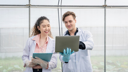 Two Agricultural researchers in the Industrial greenhouse analyze and research complex to produce better results in the future.