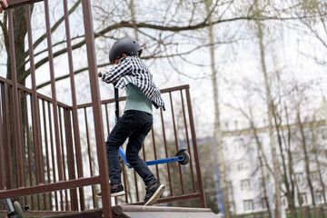 A boy on a scooter and in protective helmet do incredible stunts in skate park. Extreme jump. The...