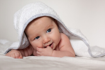 a small baby lies on the bed in a towel.Baby care.