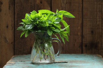 Bunches of mint in jugs on a wooden background