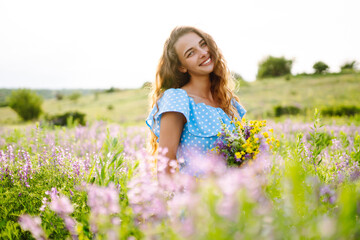 Naklejka na ściany i meble Beautiful woman in the blooming field. Nature, vacation, relax and lifestyle. Summer landscape.