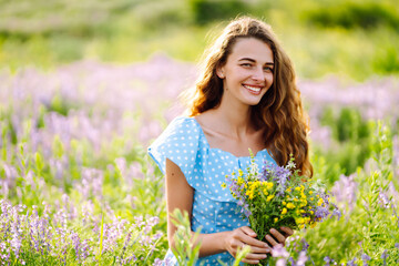 Naklejka na ściany i meble Beautiful woman in the blooming field. Nature, vacation, relax and lifestyle. Summer landscape.