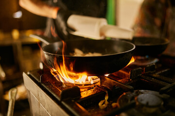 flame in the pan. Professional Chef makes flambe for food in the restaurant kitchen. Chef cooking...