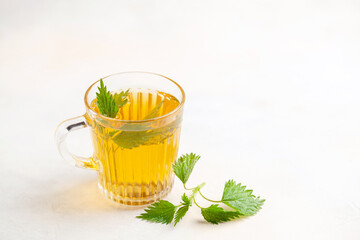 Herbal nettle tea in a glass cup on the table.