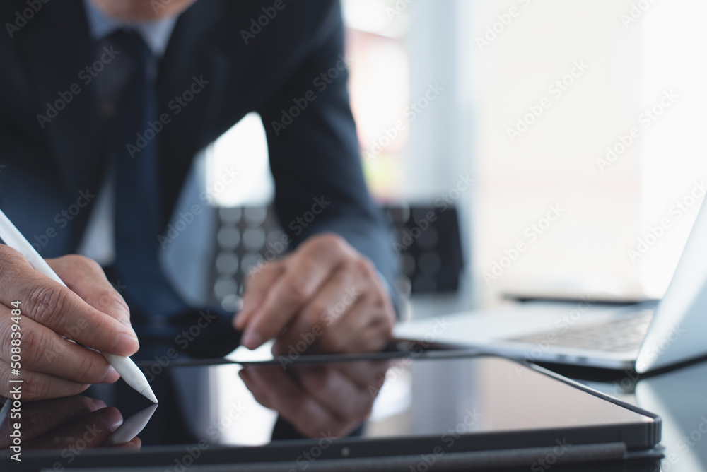 Poster businessman using stylus pen signing e-document on digital tablet with laptop computer on table at o