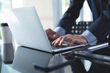 Businessman online working with laptop computer, surfing the internet, searching information with digital tableton table at office