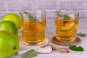 Fresh apple juice in glasses on a white wooden background.

