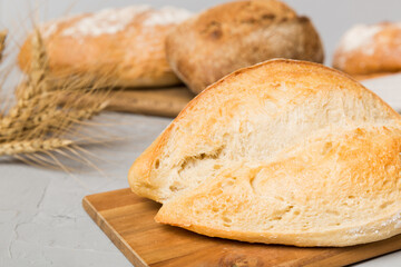 Freshly baked bread on cutting board against white wooden background. perspective view bread with copy space