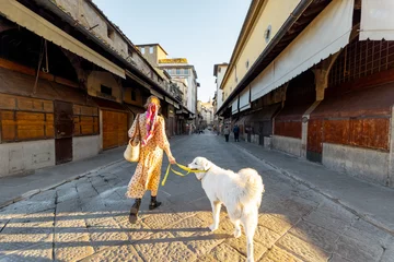 Papier Peint photo Ponte Vecchio Woman walking with dog on famous old bridge, called Ponte Vecchio, in Florence. Concept of traveling italian landmarks. Stylish woman with colorful shawl and sunglasses