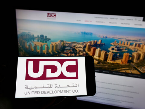 Stuttgart, Germany - 05-21-2022: Person holding mobile phone with logo of United Development Company Q.P.S.C. (UDC) on screen in front of business web page. Focus on phone display.