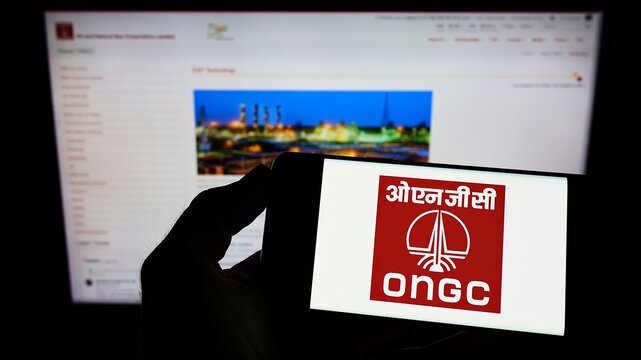 Stuttgart, Germany - 05-21-2022: Person holding mobile phone with logo of Oil and Natural Gas Corporation Limited (ONGC) on screen in front of web page. Focus on phone display.