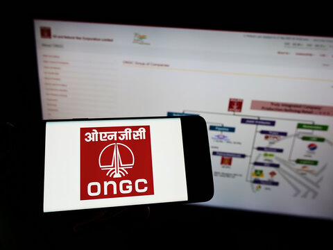 Stuttgart, Germany - 05-21-2022: Person holding smartphone with logo of Oil and Natural Gas Corporation Limited (ONGC) on screen in front of website. Focus on phone display.