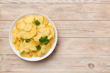 Potato chips on bowl with napkin on colored background. Delicious crispy potato chips in bowl. Space for text. Top view