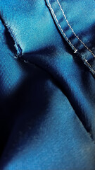 Close-up old work uniform with scuffs on a lowercase seam of blue denim