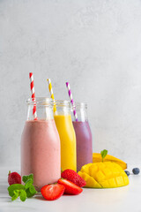 Colorful summer drinks. Fruit and berry smoothie or milkshake in bottles with straw on white background