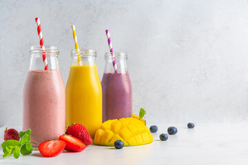 Fruit and berry smoothie in bottles with straw and fresh fruits. Summer tropical refreshing drinks
