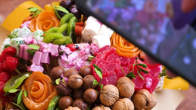 beautiful sweet bouquet of dried fruits are photographed with a phone camera. unusual gift photographs blogger.selective focus. sweet gift maker