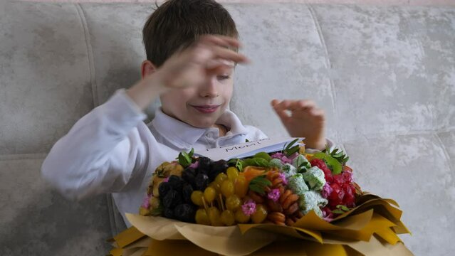 caucasian boy 7 years old wrote a congratulation for mom with the inscription i love you mom. the child prepared a gift for mother's day a bouquet of sweet dried fruits.