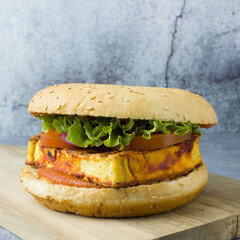 Tomato tofu burger with lettuce, tomato slices with vegan sesame bun on the cutting board