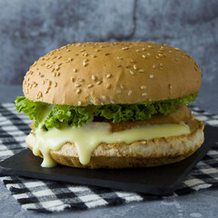Veggie burger with plant based cutlet, vegan mayonaise, lettuce, sesame bun on the black slate plate