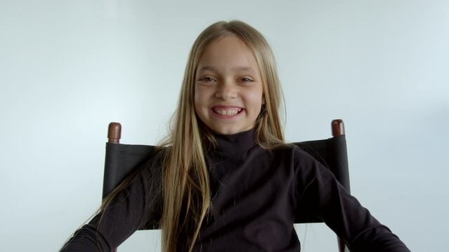 4K Footage pre-teen cute girl smiles with teeth laughs looking at the camera. Brown-eyed teenager fair-haired blond golden hair joyful childlike smile. Cheerful happy child. Baby face type young model