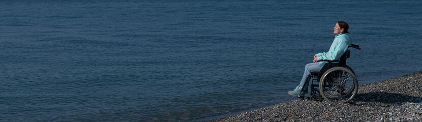 Pacified caucasian woman in a wheelchair on the seashore. 