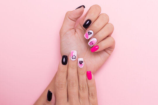 
Beautiful female hands with fashion manicure nails, hearts and Valentine's day design, on pink background