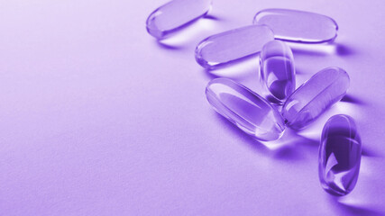 Fish oil softgels lie on a light surface. Vitamin and a healthy lifestyle. Purple tinted background...