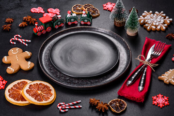 Christmas table setting with empty black ceramic plate, fir tree and black accessories