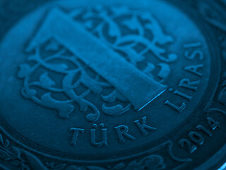 Translation: Turkish lira. Fragment of Turkish 1 one lira coin close-up. National currency of Turkey. Blue tinted money background. Backdrop for news about economy or finance. Macro