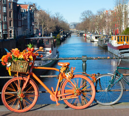 Fototapeta na wymiar Amsterdam symbolic bright decorated bike with flowers and canal in background