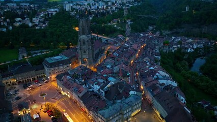 flying above historic Swiss town of Fribourg at night, aerial view of Fribourg in Switzerland with night illumination, tourism in Switzerland concept