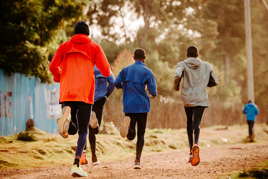 Kenyan long distance runners train in the morning on red road. Marathon training in Iten, Kenya, Home Of Champions, Eldoret. Marathon motivation, sport photo, edit space