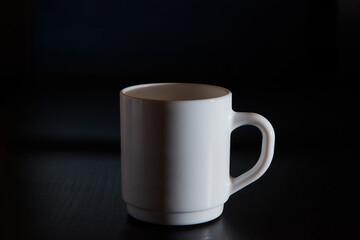 White mug for tea and coffee in on a dark background, close-up