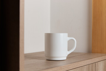 White mug for tea and coffee in on a wooden table, close-up