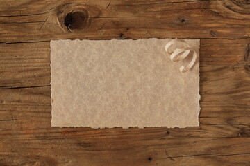 Minimalist stationery mockup, blank sheet of paper on a brown wooden background, space for wishes, thanks or notes.